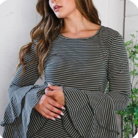 Woman wearing a olive green and white striped top with bell sleeves against a white background.