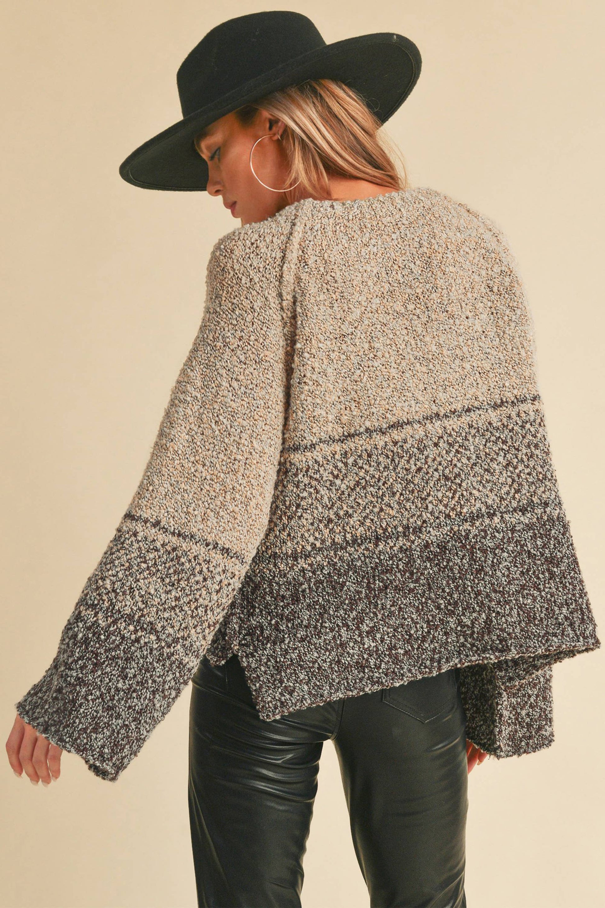 Person wearing a patterned sweater and black hat on a beige background