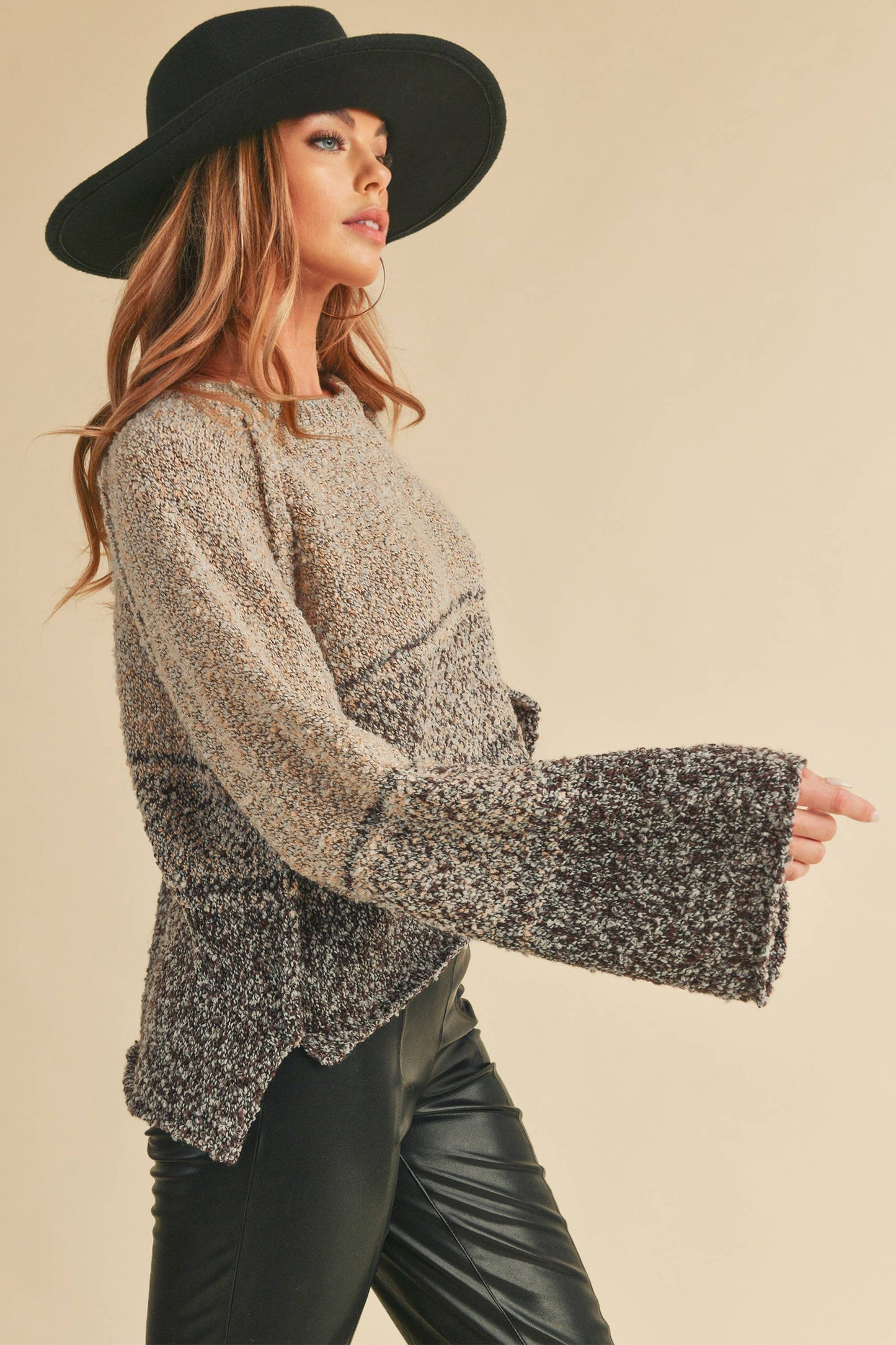 Woman wearing a patterned sweater and black hat against a beige background