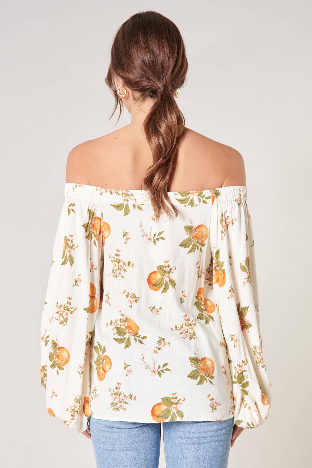 Woman wearing an off-shoulder floral blouse with a plain background
