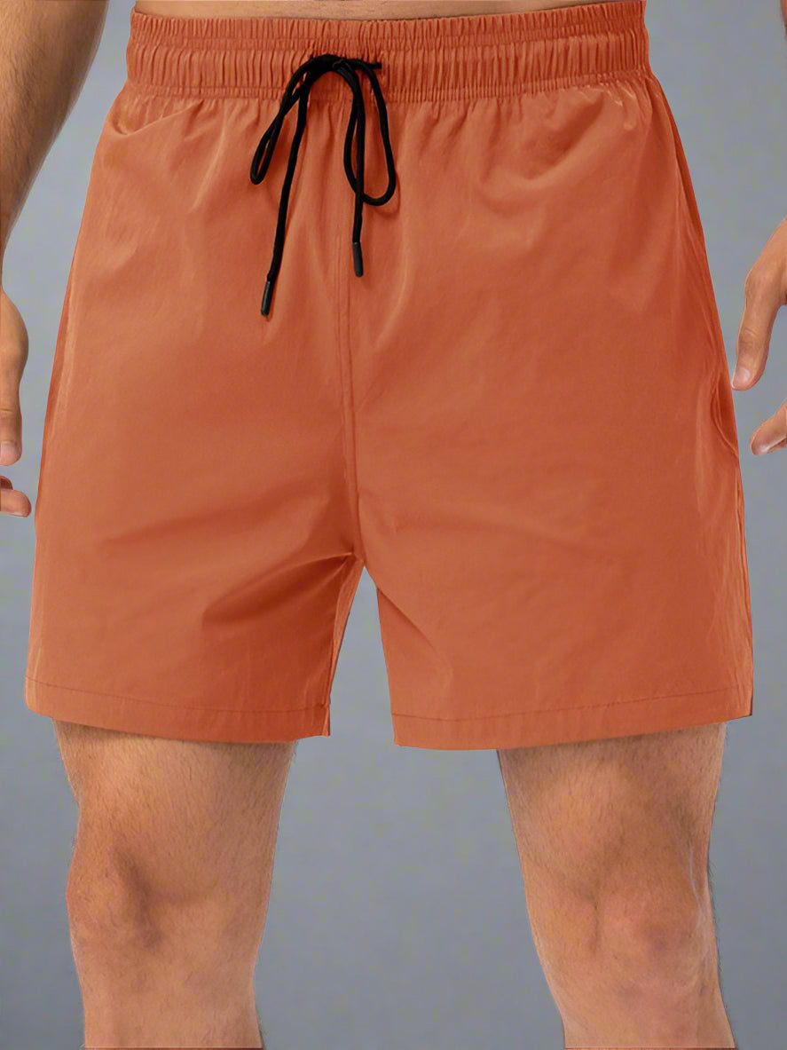 Orange swim shorts with a drawstring on a white background