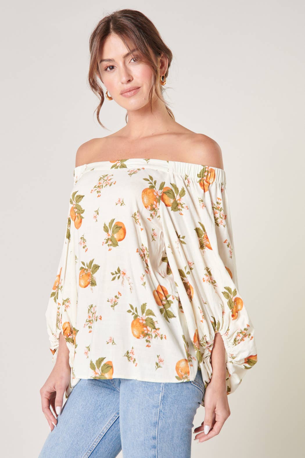 Woman wearing an off-shoulder floral top with a plain background