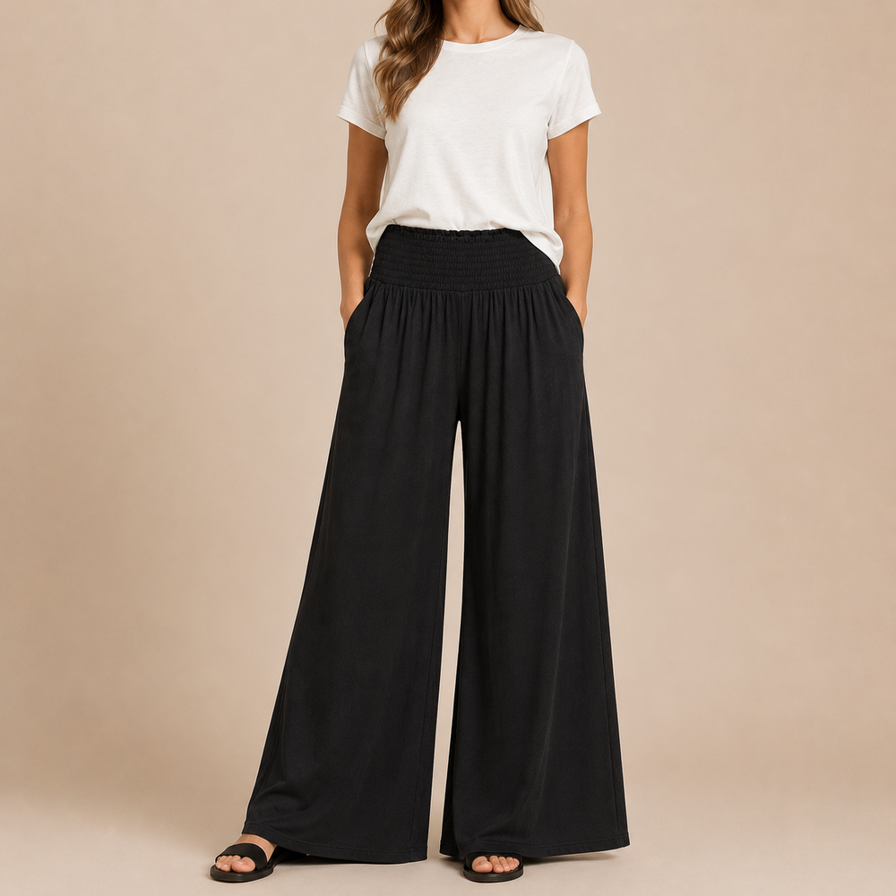 Person wearing a white t-shirt and black wide-leg pants on a beige background