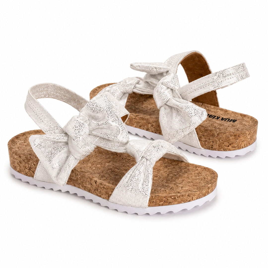 White sandals with cork sole and bow design on a white background
