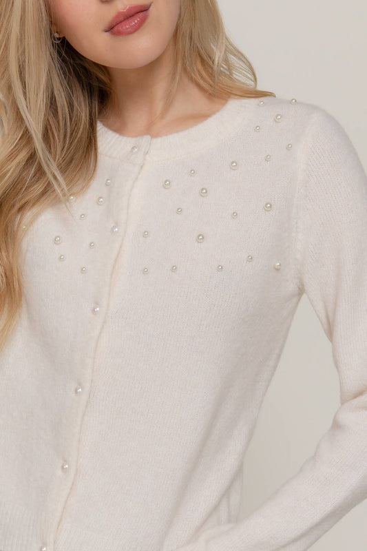Close-up of a white blouse with pearl embellishments on a plain background