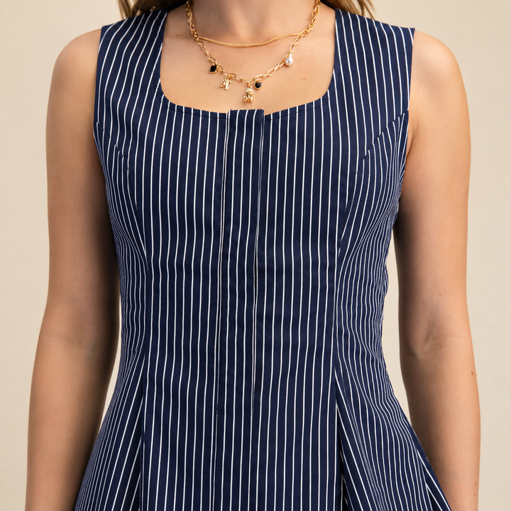 Navy pinstripe dress worn by a person on a beige background