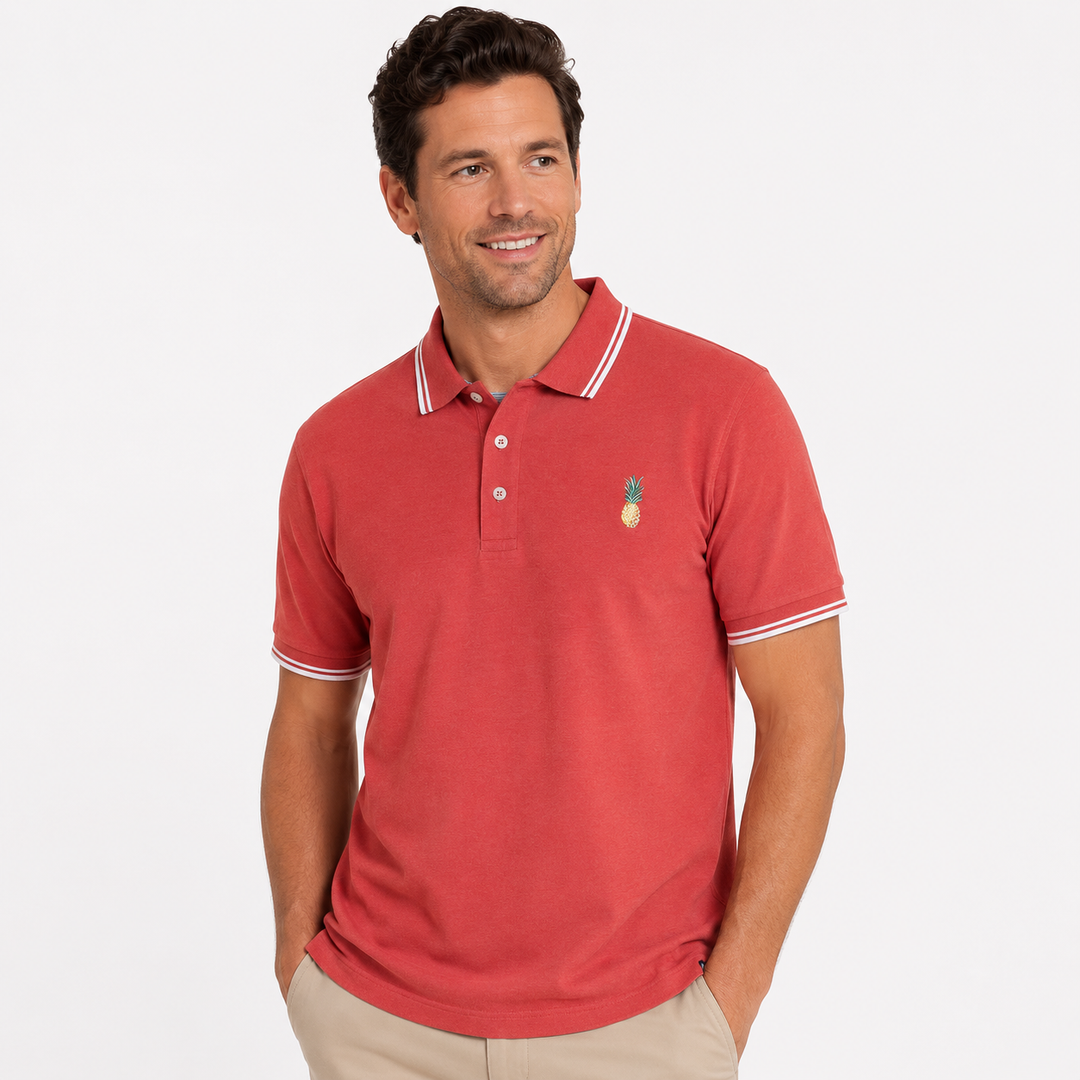 Man wearing a pinkish polo shirt with a pineapple emblem on a white background