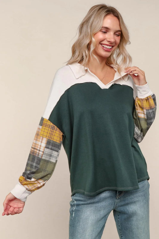 Woman wearing a green and plaid long-sleeve top with jeans on a beige background