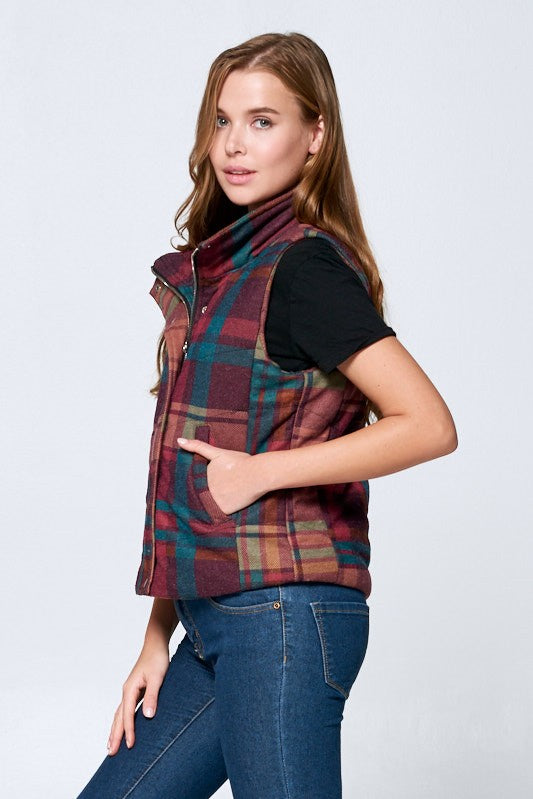 Woman wearing a plaid vest over a black shirt with blue jeans on a white background