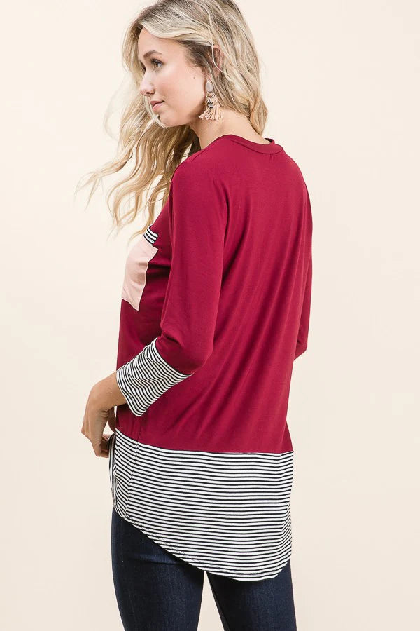 Woman wearing a red long-sleeve top with a striped pattern at the bottom on a beige background