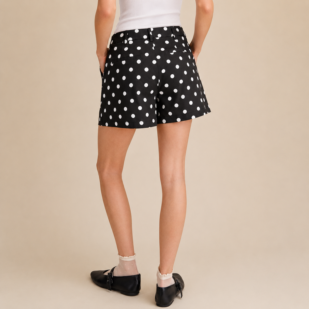 Person wearing black polka dot shorts on a beige background