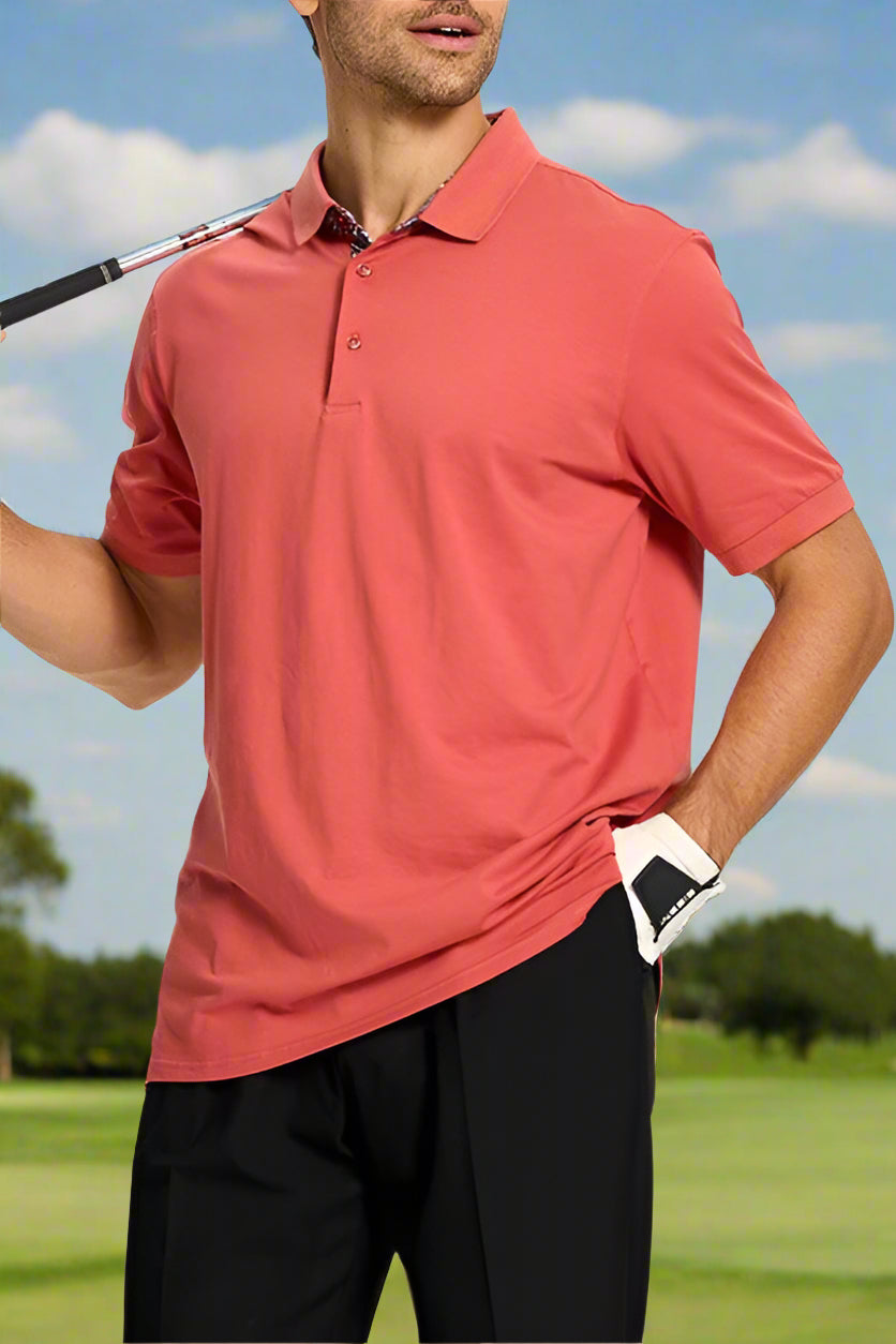 Man wearing a red polo shirt and black pants, holding a golf club.