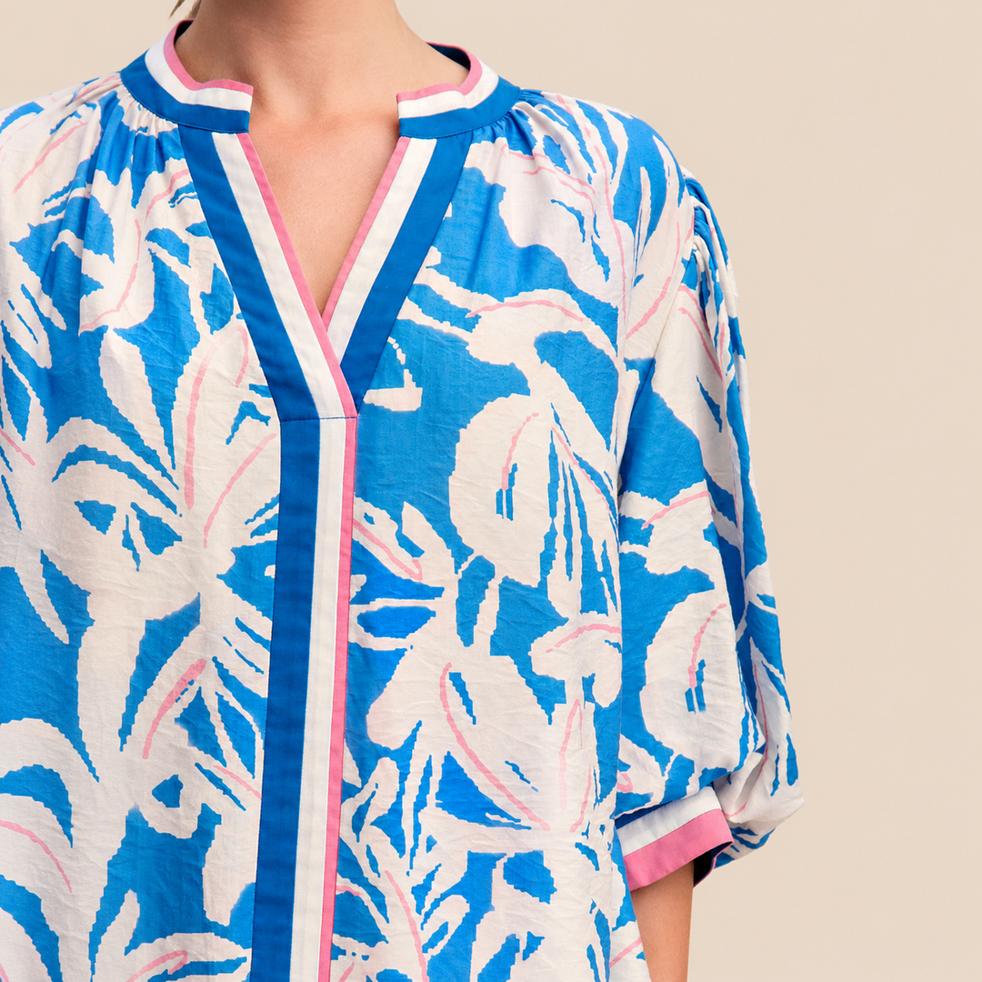 Blue and white floral patterned garment with pink trim on a beige background