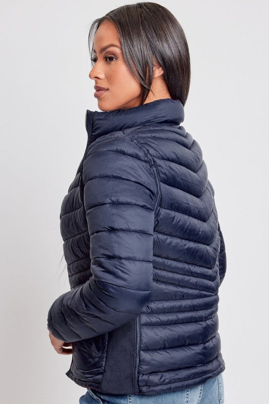 Woman wearing a navy blue puffer jacket on a light gray background