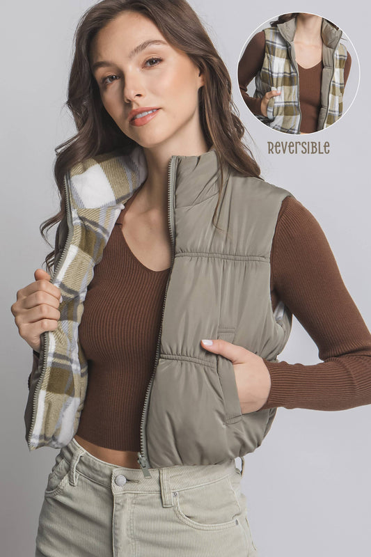 Woman wearing a reversible vest with plaid and solid colors, on a gray background.