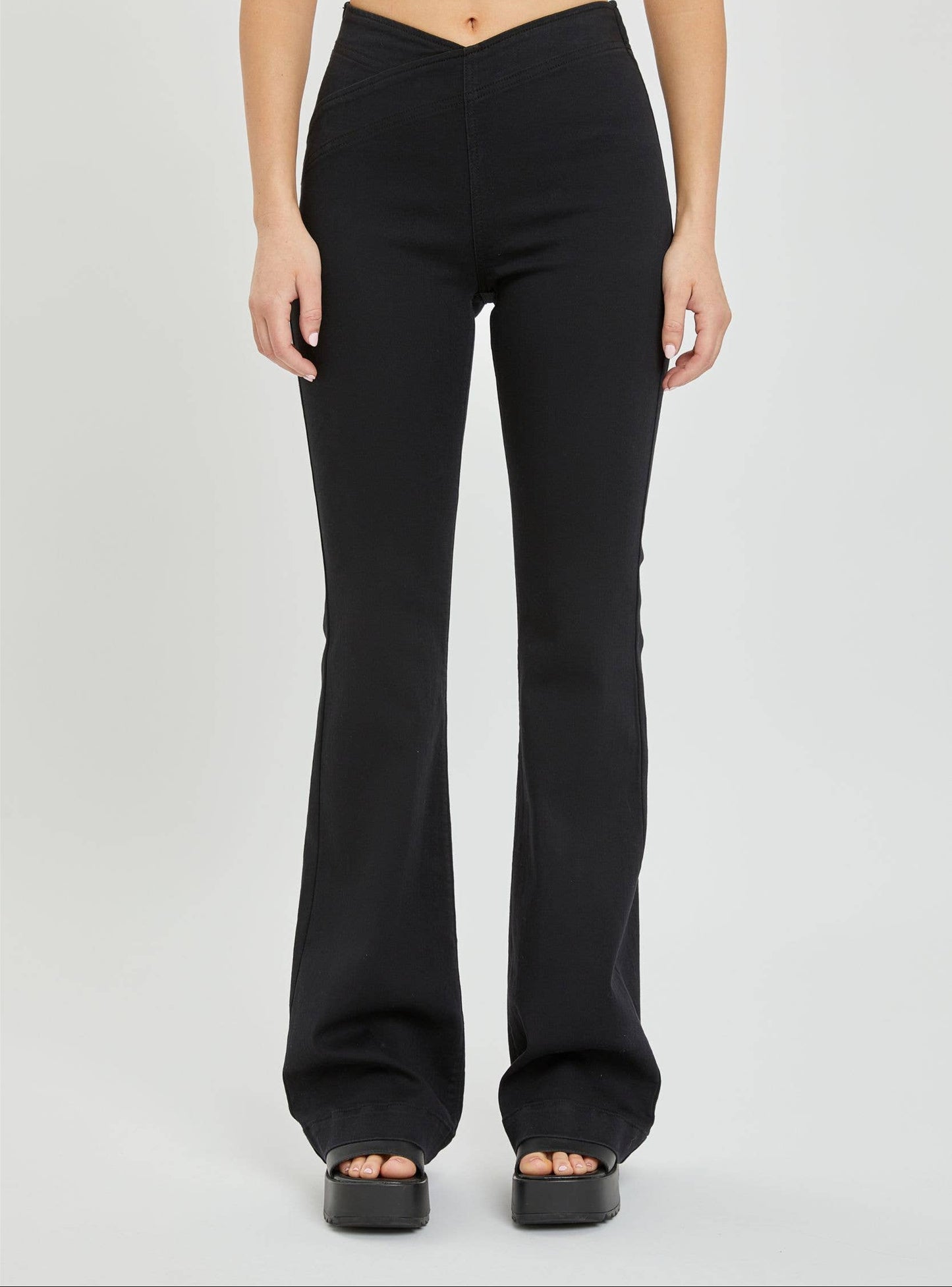 Black flared pants worn by a person on a white background