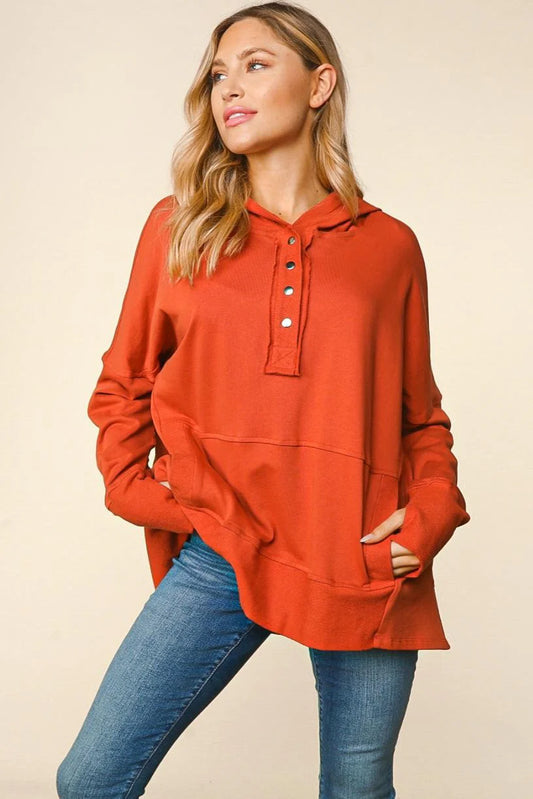 Woman wearing a red hoodie and blue jeans against a beige background