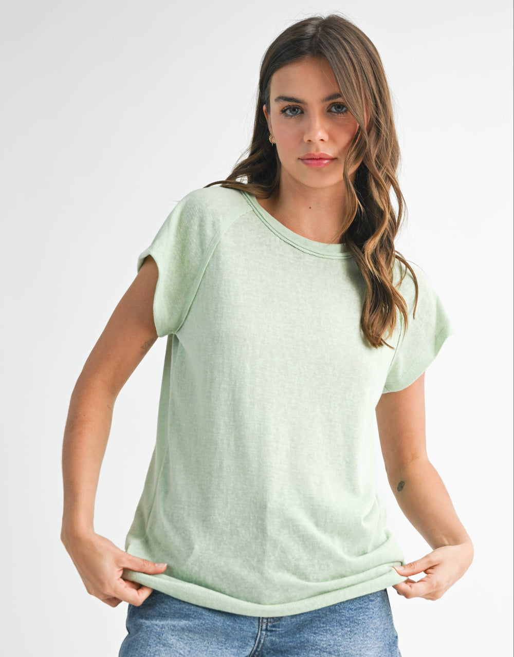 Woman wearing a light green t-shirt and denim shorts on a white background