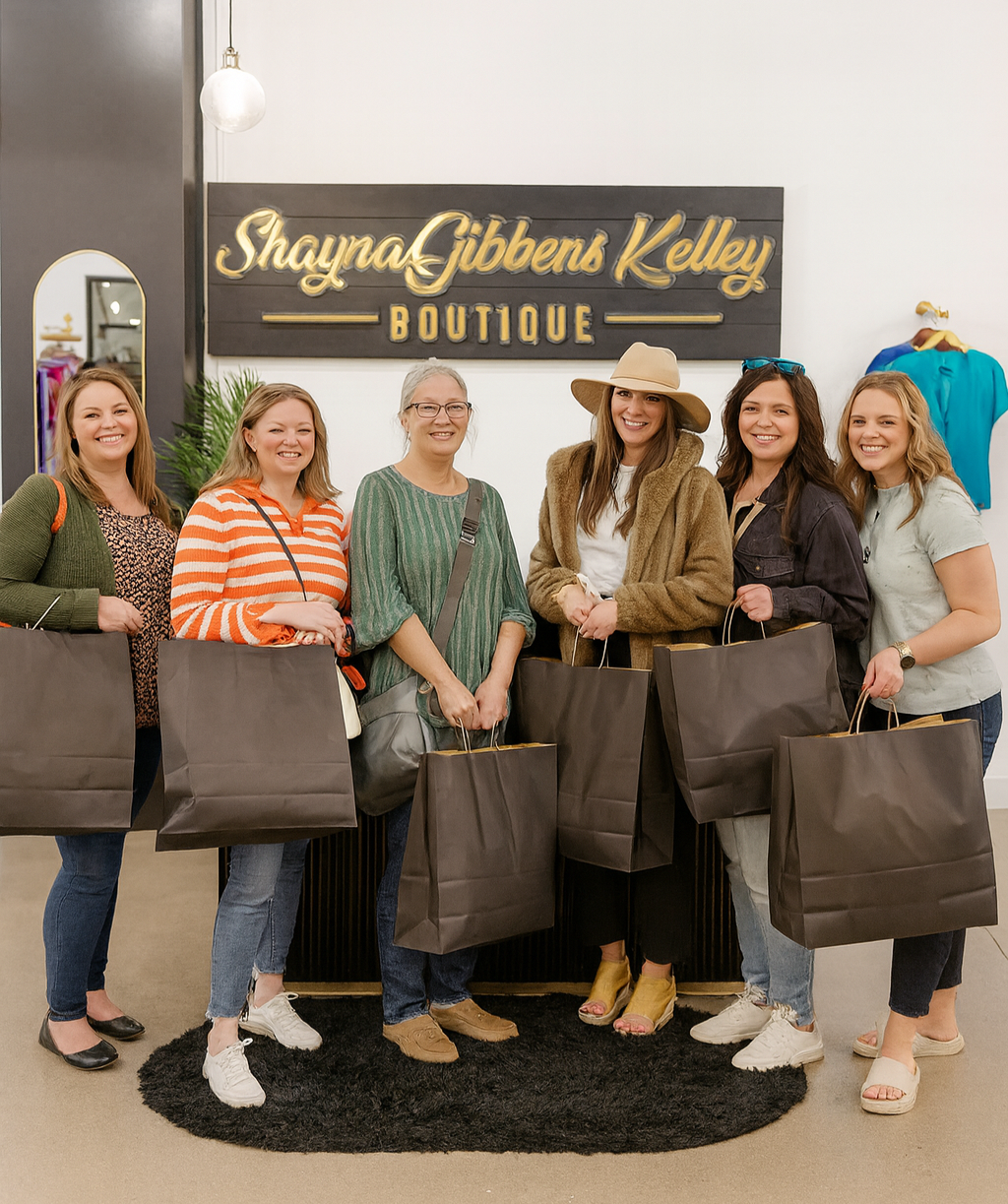 Group of women holding brown bags in front of a 'Shayna Gibbens Kelley Boutique' sign.