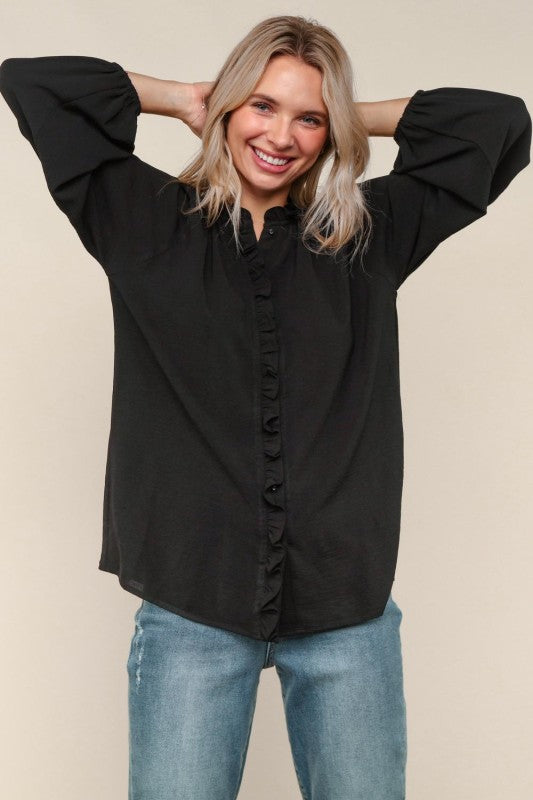 Woman wearing a black blouse and blue jeans against a beige background