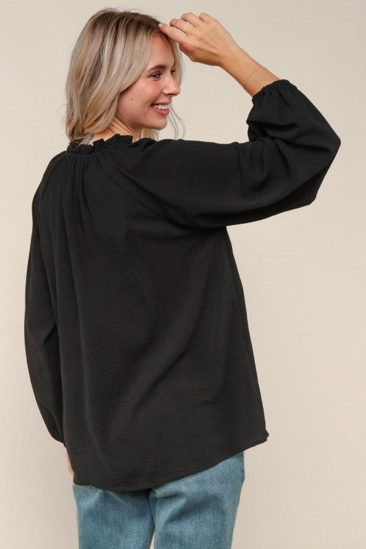 Woman wearing a black oversized sweater against a beige background