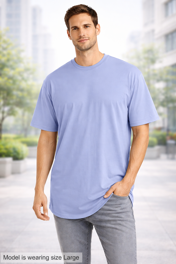 Man wearing a light blue t-shirt and gray pants standing outdoors with blurred background