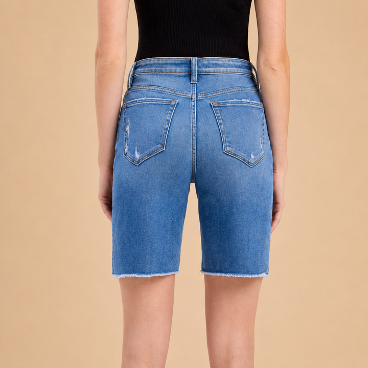 Blue denim shorts worn by a person on a beige background