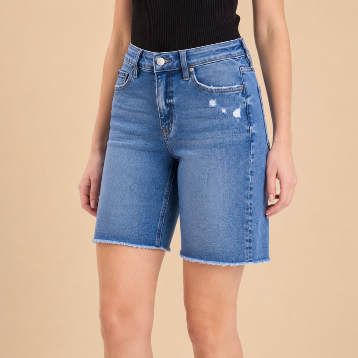 Person wearing blue denim shorts on a beige background
