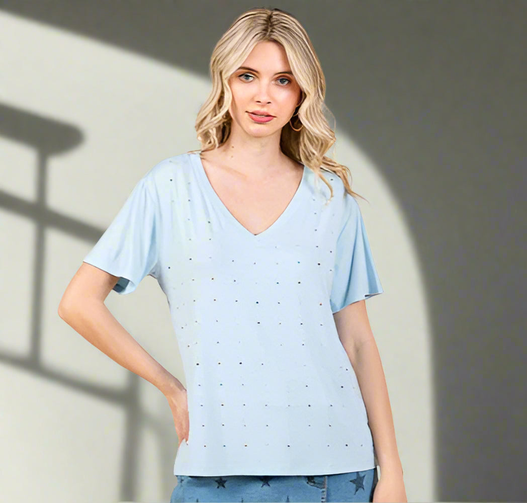 Woman wearing a light blue V-neck top with a subtle pattern on a beige background