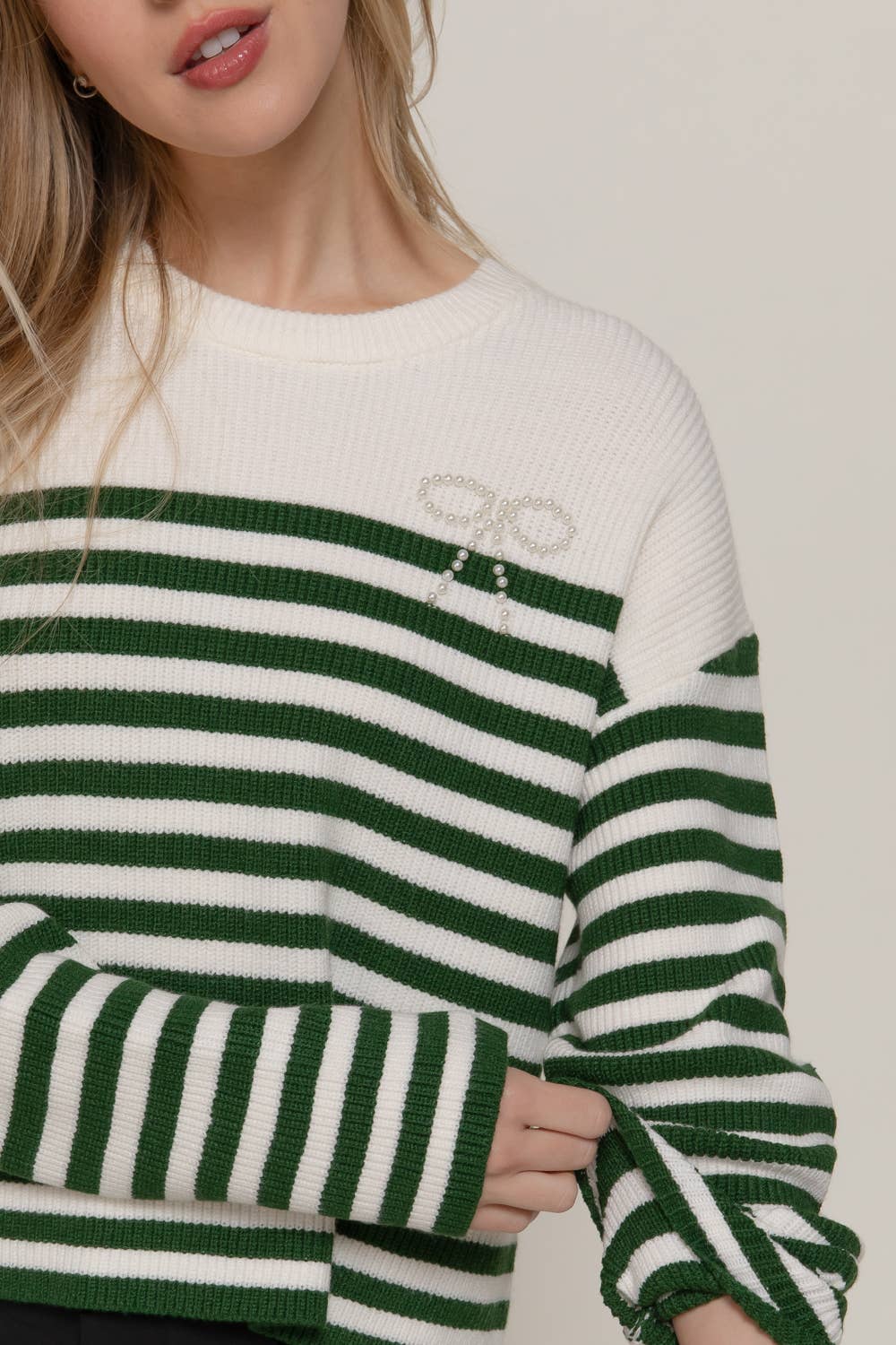 Green and white striped sweater worn by a person on a plain background