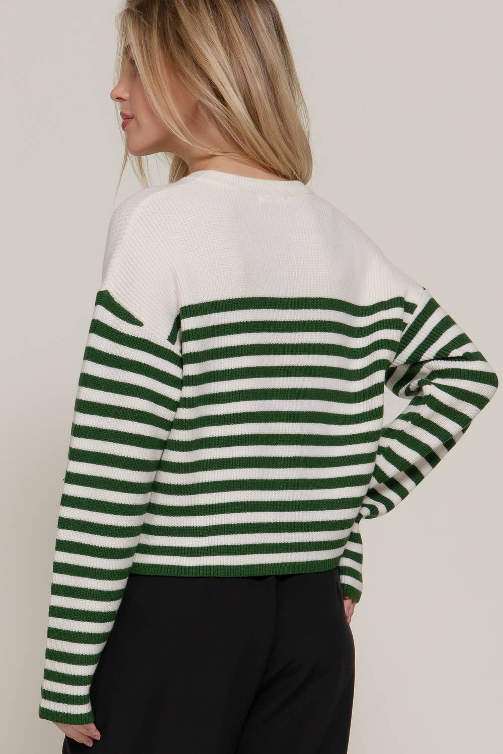 Person wearing a green and white striped sweater against a plain background