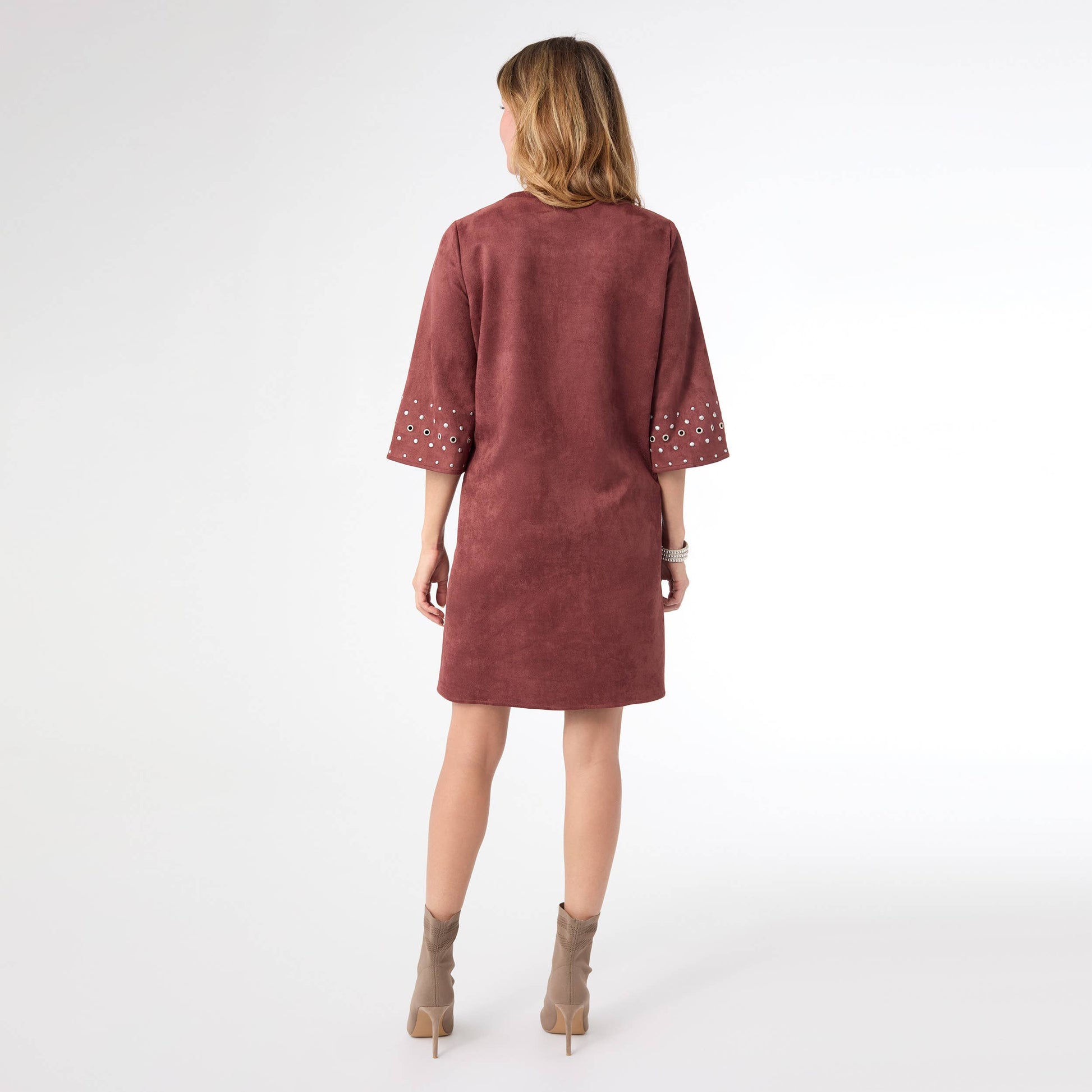 Woman wearing a maroon dress with embellishments on a white background
