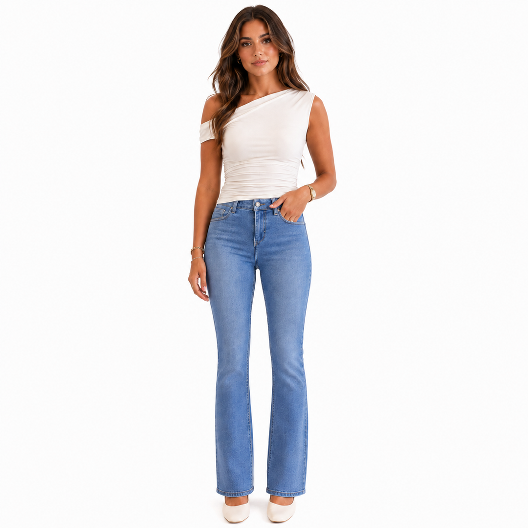 A woman modeling a white one-shoulder top and light blue flared jeans against a plain white background.
