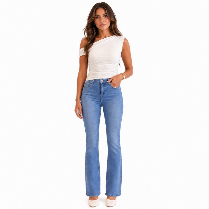 A woman modeling a white one-shoulder top and light blue flared jeans against a plain white background.