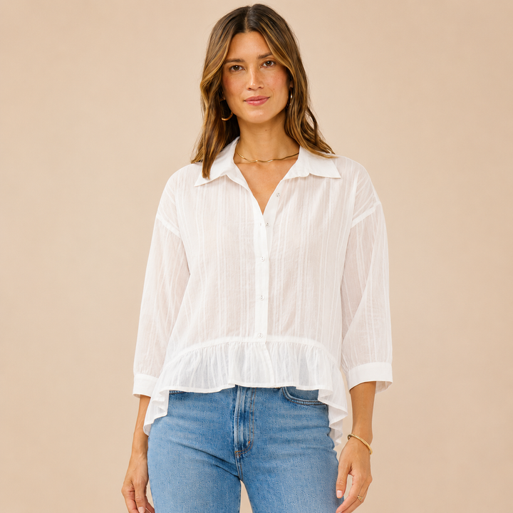 Woman wearing a white blouse and blue jeans against a beige background