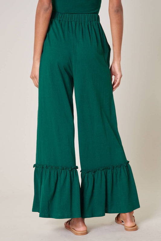 Green wide-leg pants with ruffled bottom hem on a neutral background