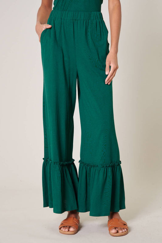 Green ruffled pants worn by a person on a plain background