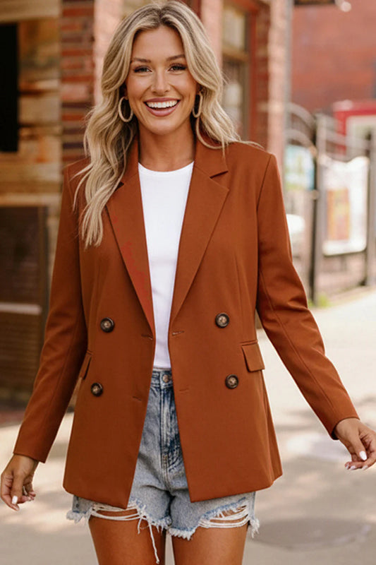 Woman wearing a brown blazer over a white top and denim shorts, standing on a street.