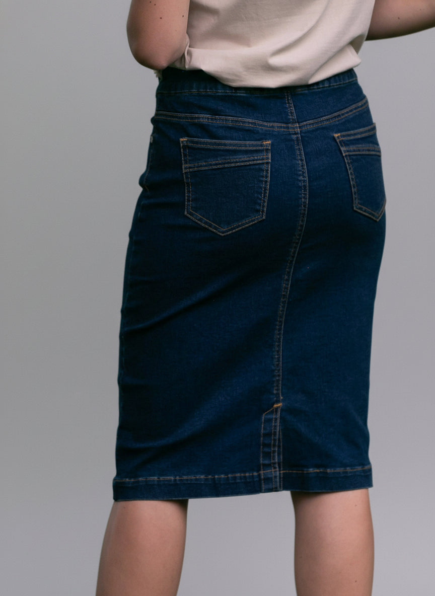 Person wearing a blue denim skirt with a blurred green background