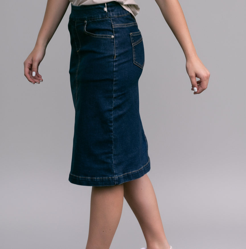 Person wearing a blue denim skirt standing on grass with a blurred background