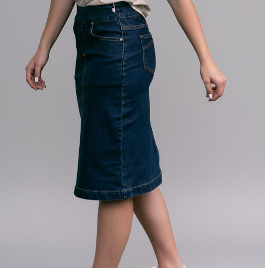 Person wearing a blue denim skirt standing on grass with a blurred background