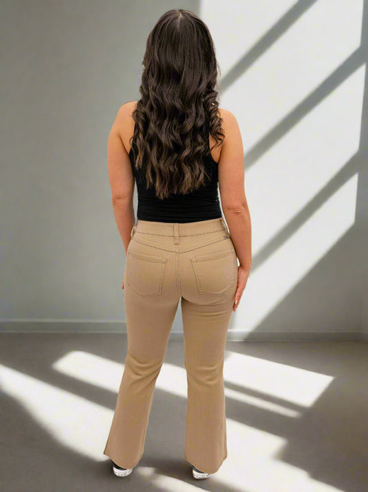 Woman wearing beige pants and a black top on a white background