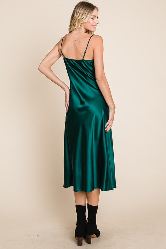 Woman wearing a green satin slip dress against a beige background
