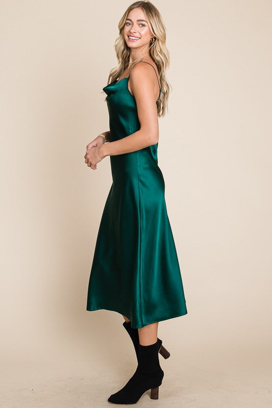 Woman wearing a green satin dress against a beige background