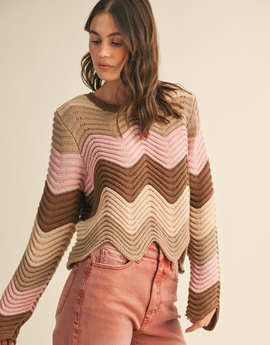 Woman wearing a colorful striped sweater and pink pants on a beige background