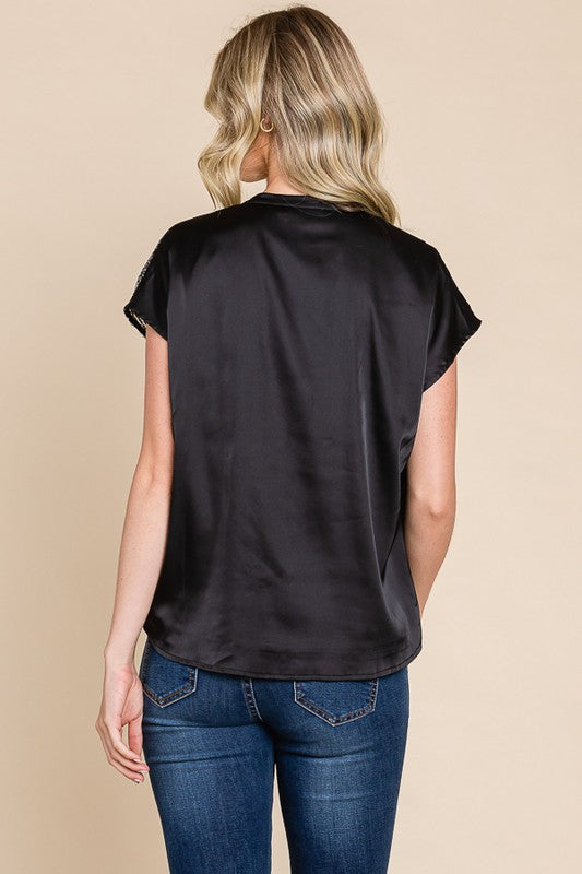 Woman wearing a black top and blue jeans on a beige background