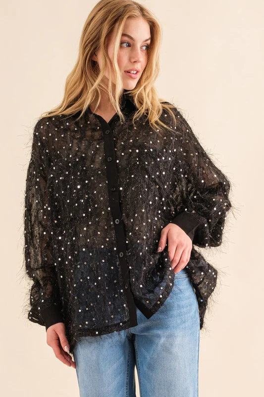 Woman wearing a black sequin blouse and blue jeans on a beige background