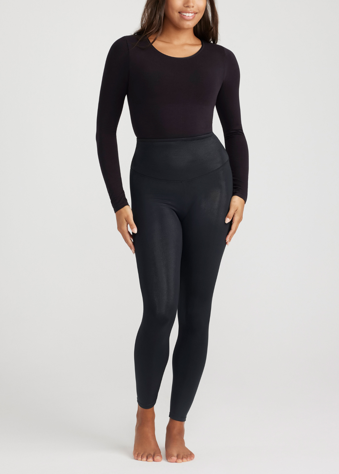 Person wearing a black long-sleeve top and leggings on a white background