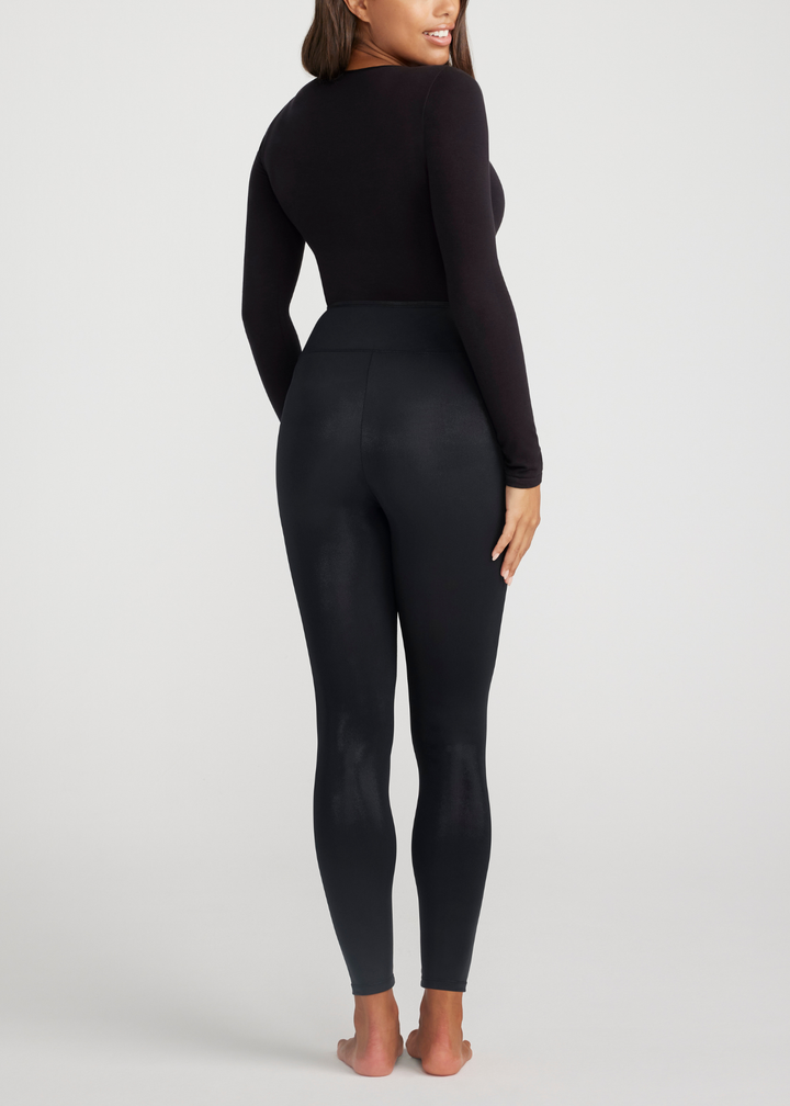 Person wearing a black long-sleeve top and leggings on a light gray background
