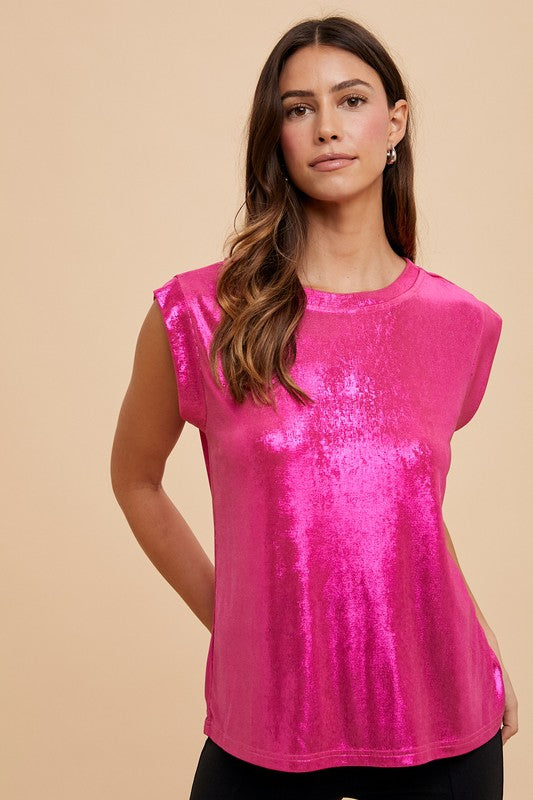 A woman wearing a sleeveless, round neck, shimmering metallic pink knit tee.